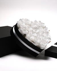 Eighteen white preserved roses in a black heart-shaped box