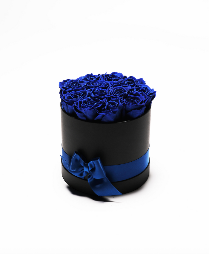 Twelve sapphire blue preserved roses in a black round hat box