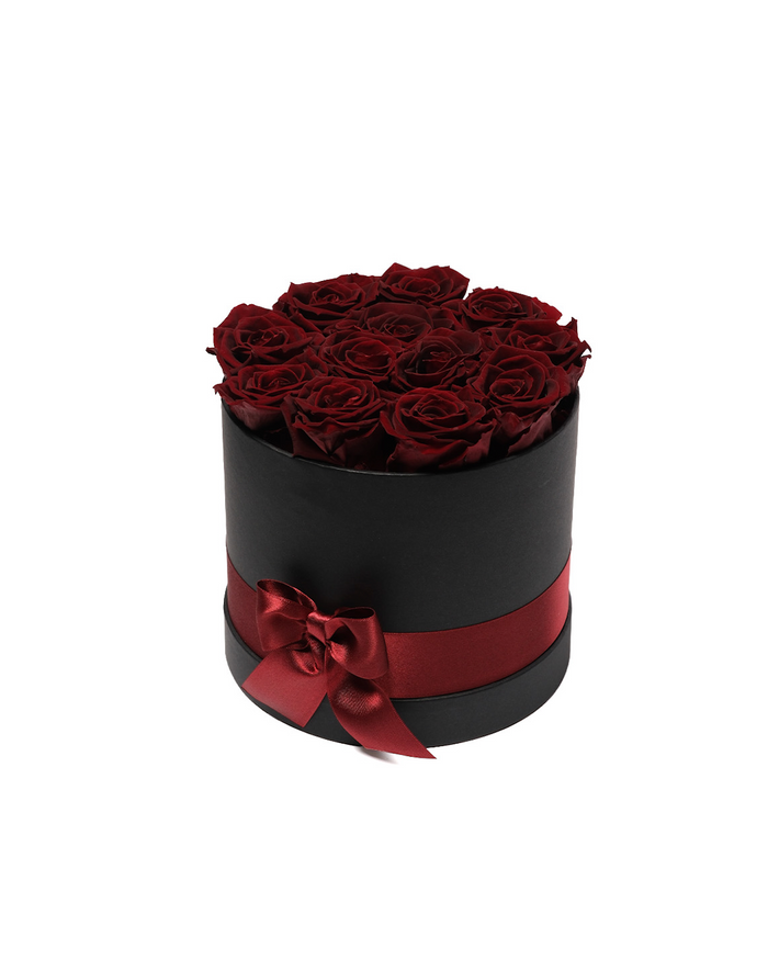 Twelve burgundy preserved roses in a black round hat box
